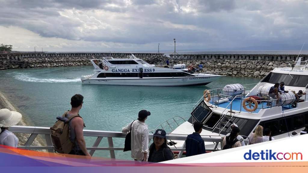 Suasana pelabuhan penyeberangan di Nusa Penida dengan aktivitas naik turun penumpang kapal cepat menuju Bali daratan.