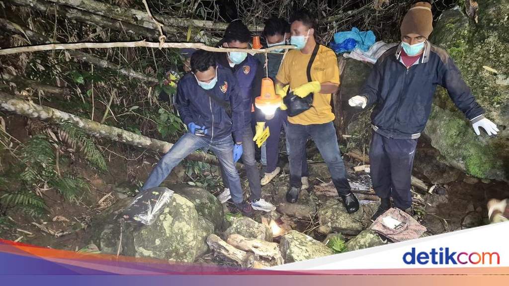Petugas kepolisian bersama warga saat melakukan proses evakuasi kerangka manusia di area anak sungai Manggarai Timur.