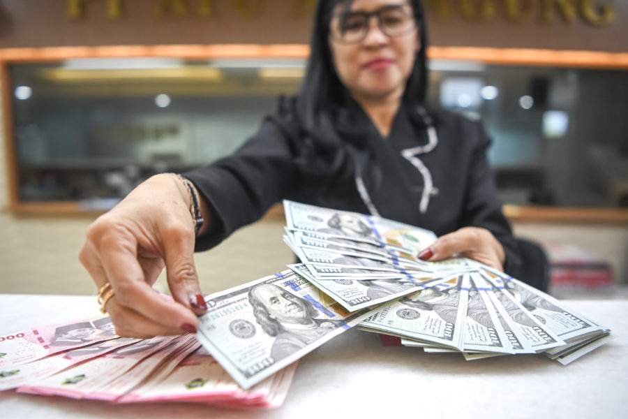 Aktivitas pekerja saat menghitung lembaran mata uang rupiah dan dolar Amerika Serikat di salah satu gerai penukaran resmi di Jakarta.
