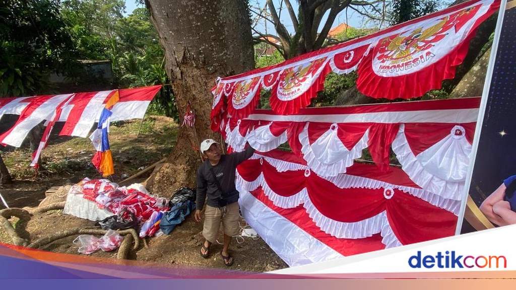 Seorang pedagang bendera musiman sedang merapikan jajaran bendera Merah Putih yang dipajang di pinggir Jalan Diponegoro Karangasem Bali.