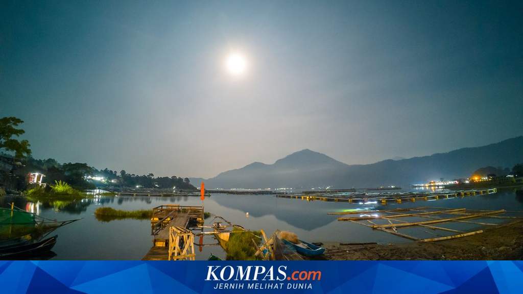 Pemandangan Danau Batur di kawasan Kintamani, Bali, dengan latar Gunung Batur di bawah langit berawan cerah.